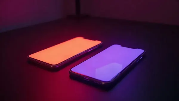Dwa smartfony obok siebie, jeden pomarańczowy, drugi fioletowy, neonowe refleksy (ilustracja do artykułu)